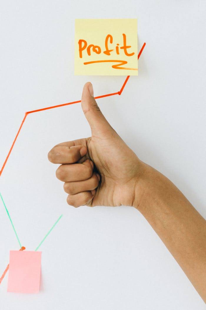 A hand giving a thumbs up in front of a profit growth chart, highlighting success.